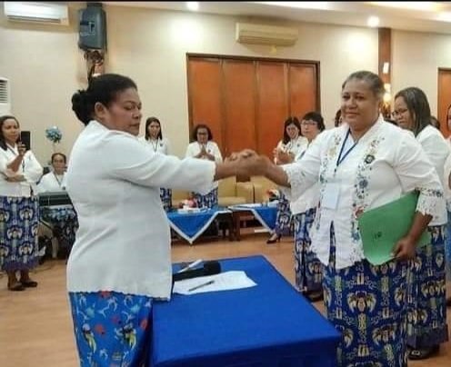 Ketua DPC PWKI Mimika, Maryana Joice Eveline Hamadi (pegang map) berjabatan tangan dengan Ketua DPD PWKI Papua setelah tanda tangan berita acara pemilihan.