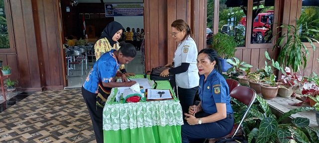 Agustina Rahadet, Kasubid Penanggulangan Kebakaran BPBD Mimika menunggu peserta sosialisasi di meja panitia untuk registrasi.