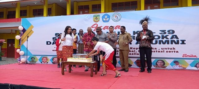 Salah seorang guru menyalakan lilin pada kue HUT ke 39 SDI Koperapoka 1.