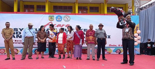 Gregorius Okoare mengangkat bunga tangan sebelum diserahkan kepada mantan Kepala Dinas Pendidikan Mimika Nikolaus Watimena.