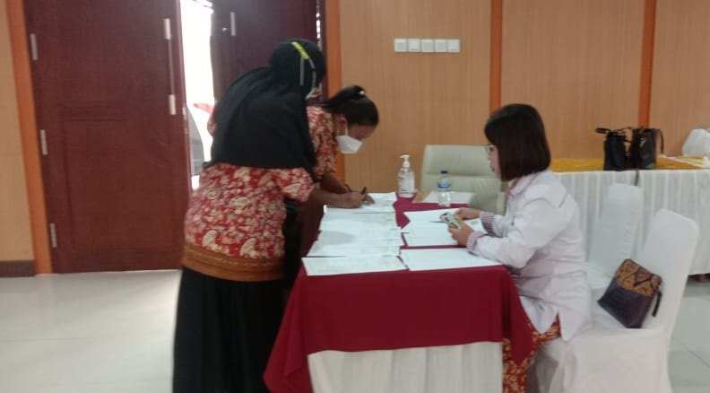 Ns Rosina Wakil Ketua Bidang Penelitian menerima tamu di meja registrasi peserta