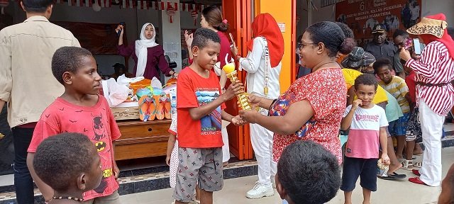 Kader Partai Buruh menyerahkan hadiah bagi anak-anak pemenang lomba gigit sendok membawa kelereng.