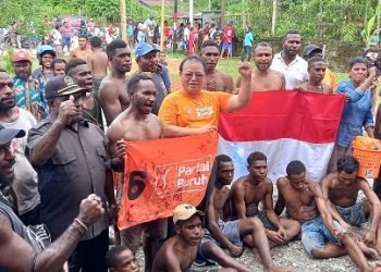 Sirhan Salilama, SH, Ketua DPC Partai Buruh Mimika bersama kader Buruh foto bersama para pemanjat pinang sambil membentangkan bendera Merah Putih dan bendera Buruh, Kamis 17 Agustus 2023.( Foto : Redaksi/Koranpapua.id)