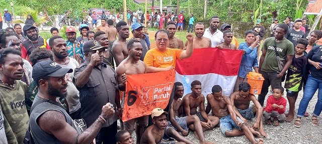 Sirhan Salilama, SH, Ketua DPC Partai Buruh Mimika bersama kader Buruh foto bersama para pemanjat pinang sambil membentangkan bendera Merah Putih dan bendera Buruh, Kamis 17 Agustus 2023.( Foto : Redaksi/Koranpapua.id)