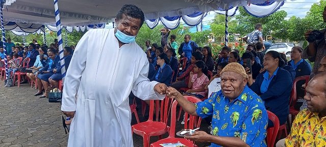 RD Samuel Ohoilejaan, Pastor Paroki Santa Sisilia menyerahkan kue kepada Ignatius Adii, Ketua FKUB Mimika.