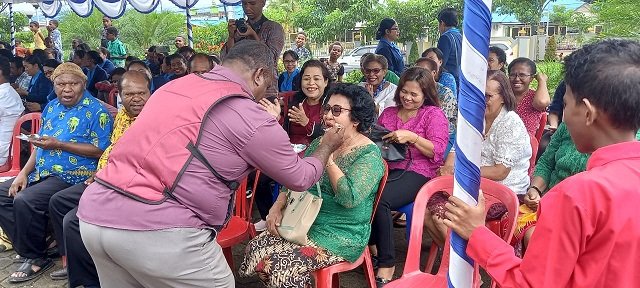 Bernolfus Welerubun, Ketua Dewan Paroki Santa Sisilia menyuapi salah satu anggota WKRI Paroki Santo Stefanus Sempan.